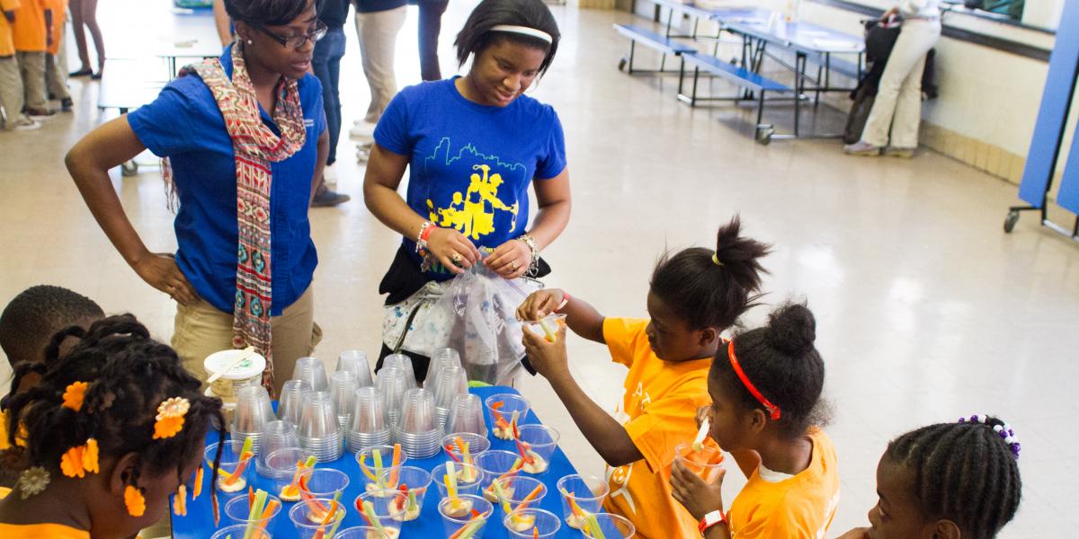 children creating healthy snacks with adults